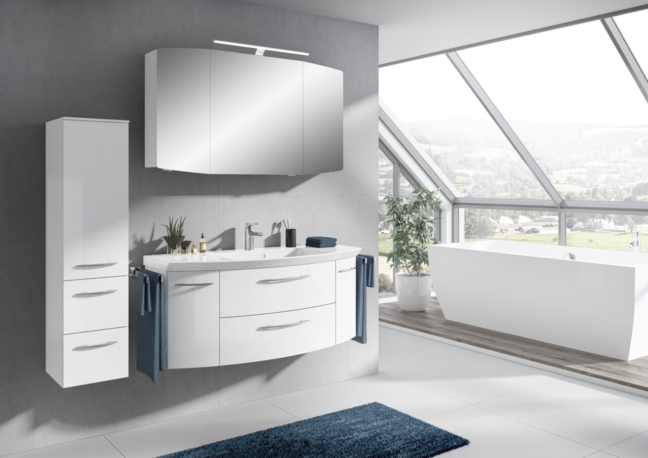 Moderne Badkombination mit weißem Waschtisch, Spiegel und Schrank, seitliche Perspektive mit Blick auf eine große Fensterfront.