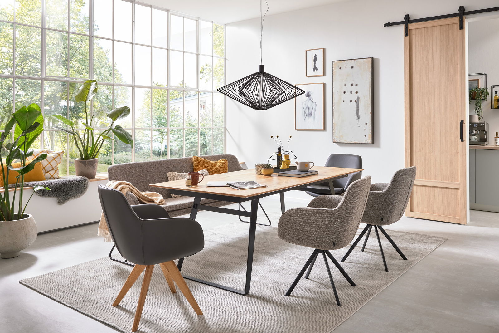 Esszimmer mit modernem Esstisch aus Holz und stilvollen Sesseln in einem hellen Raum mit großen Fenstern, seitliche Perspektive