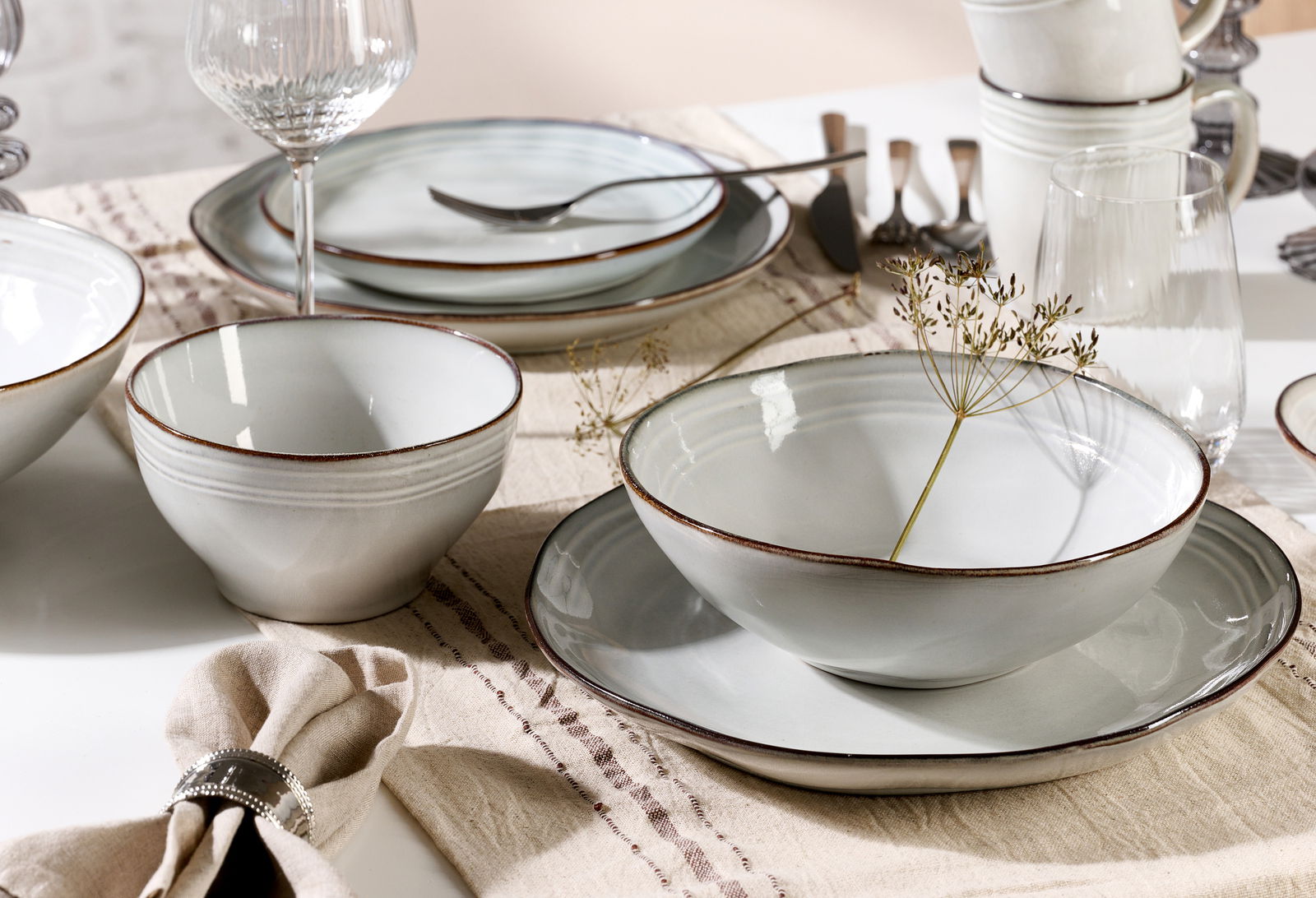 Elegantes 18-teiliges Tellerset in sanften Erdtönen, präsentiert auf einem gedeckten Tisch aus der Vogelperspektive.