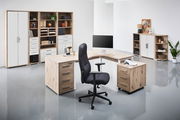 Moderner Drehstuhl in einem stilvollen Büro mit Holzschreibtisch und Regalen, seitliche Perspektive.