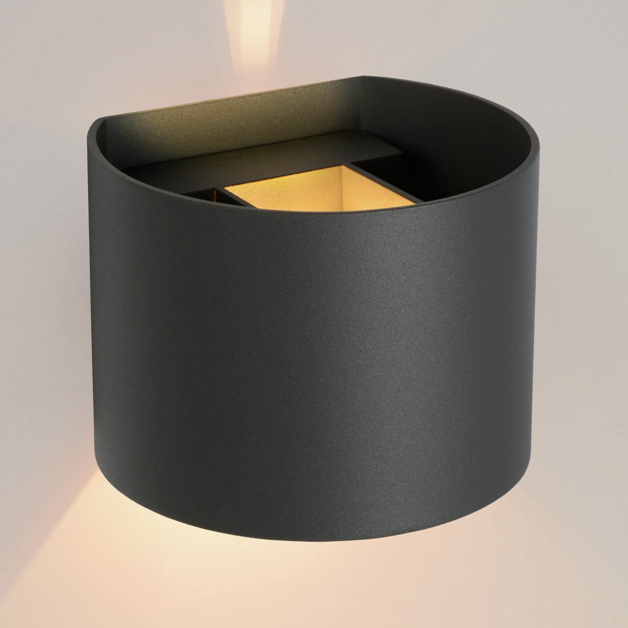 Moderne zwarte wandlamp XIO met een cilindrisch ontwerp, die zowel naar boven als naar beneden licht verspreidt. Zijaanzicht.
