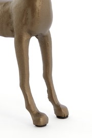 Nahaufnahme der Beine eines bronzefarbenen Tierornaments, von der Seite betrachtet.