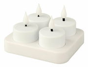 Vier weiße, wiederaufladbare LED-Teelichter auf einer quadratischen Ladestation, Ansicht von oben.