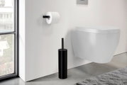 Modernes Badezimmer mit wandhängendem WC, schwarzer WC-Bürstengarnitur am Boden und Toilettenpapierhalter an der Wand, seitliche Perspektive