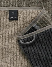 Nahaufnahme eines gestreiften Duschtuchs in verschiedenen Grautönen mit einem Joop-Label.