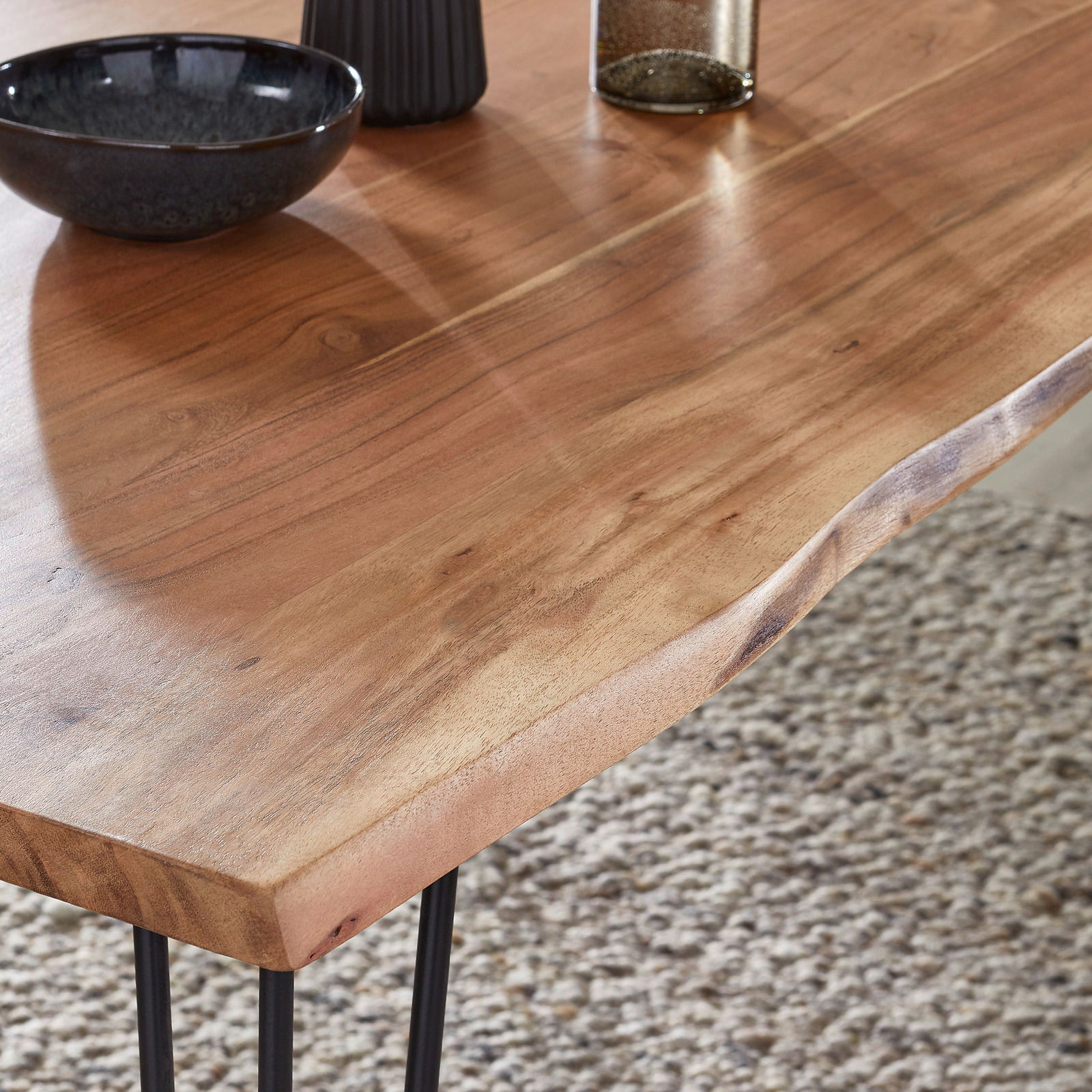 Nahaufnahme eines Esstisches aus Holz mit natürlicher Maserung und Metallbeinen, Perspektive von oben.