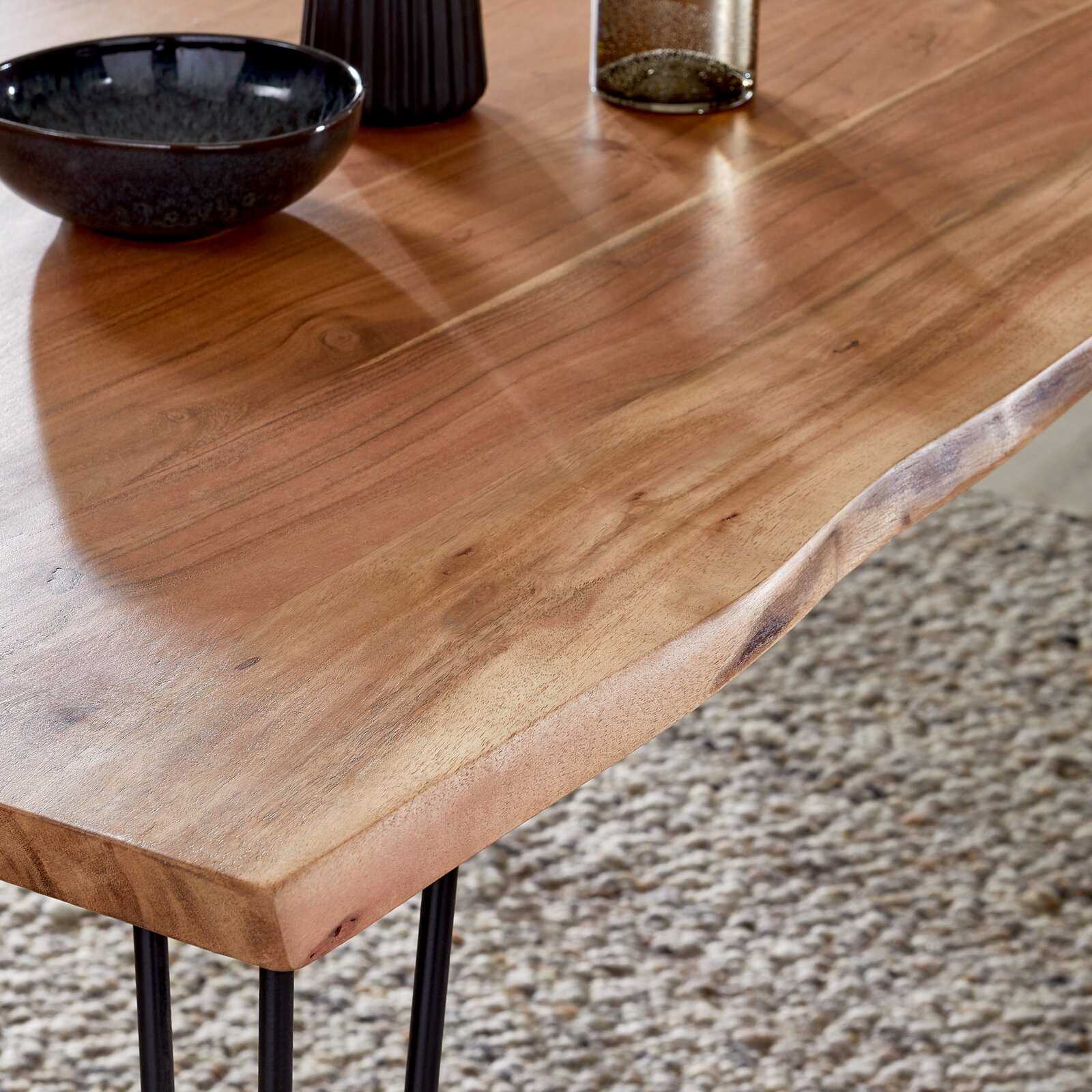Nahaufnahme eines Esstisches aus Holz mit natürlicher Maserung und Metallbeinen, Perspektive von oben.