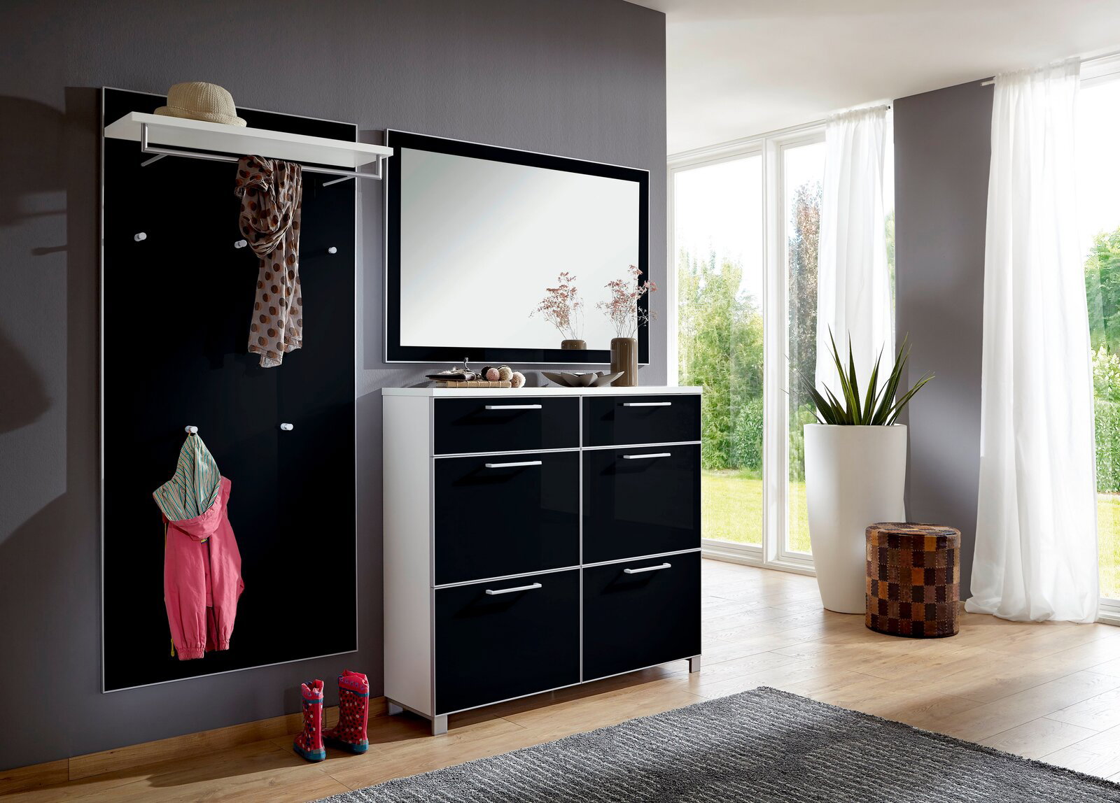 VOSS Garderoben-Set 3-tlg. SANTINA Modernes Garderoben-Set in einem hellen Raum mit großem Fenster, bestehend aus einer schwarzen Wandpaneele mit Haken, einem weißen Regalbrett und einem schwarzen Schuhschrank mit Spiegel. Perspektive von vorne.
