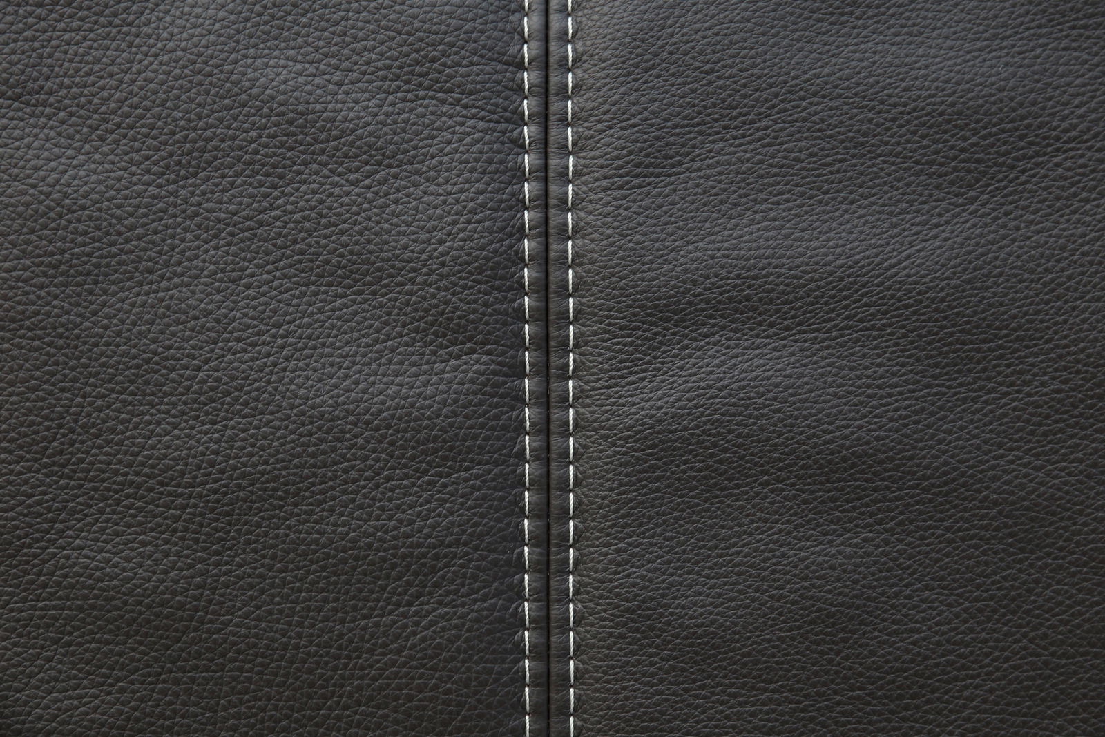Nahaufnahme einer schwarzen Lederoberfläche mit sichtbarer Naht in der Mitte, von oben betrachtet.