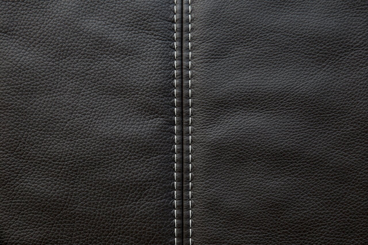 Nahaufnahme einer schwarzen Lederoberfläche mit sichtbarer Naht in der Mitte, von oben betrachtet.
