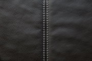 Nahaufnahme einer schwarzen Lederoberfläche mit sichtbarer Naht in der Mitte, von oben betrachtet.