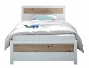 Modernes Bett mit weißem Rahmen und Holzakzenten, frontal fotografiert. Auf dem Bett liegt eine Zeitschrift und eine Sonnenbrille.
