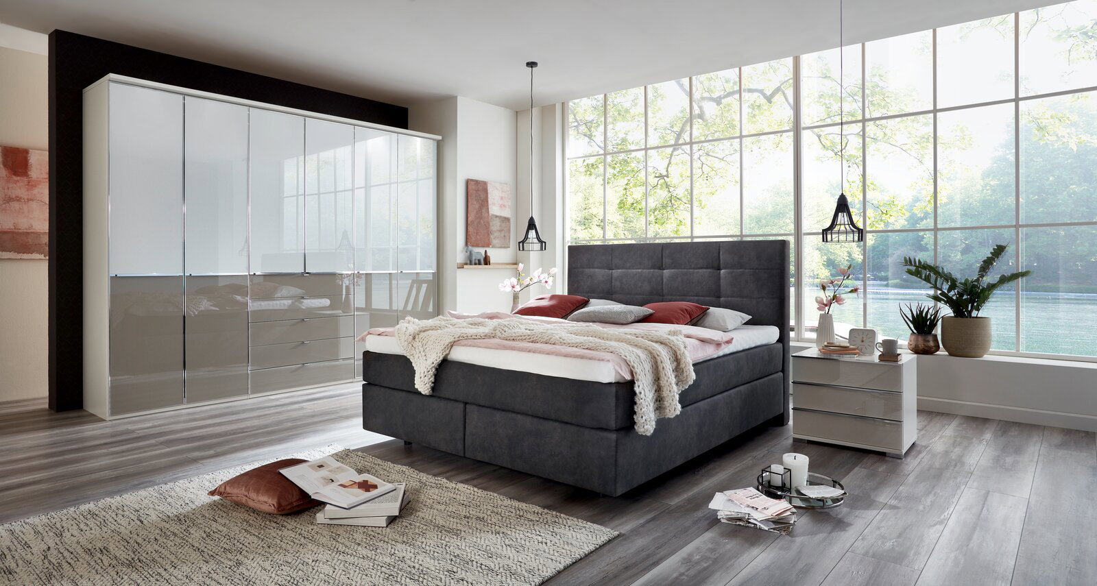 Modernes Boxspringbett in einem stilvollen Schlafzimmer mit großen Fenstern, seitliche Perspektive.