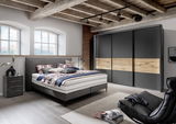 Modernes Boxspringbett in einem stilvollen Schlafzimmer mit Holzbalkendecke, seitliche Perspektive.