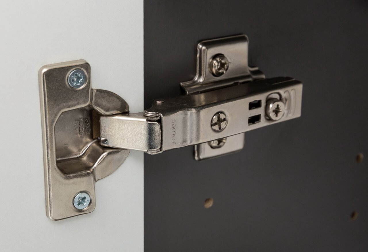Nahaufnahme eines Metallscharniers an einem Hängeschrank, seitliche Perspektive