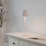 Elegante Akku-Tischleuchte BOTERIA in Weiß auf einem Tisch, seitliche Perspektive