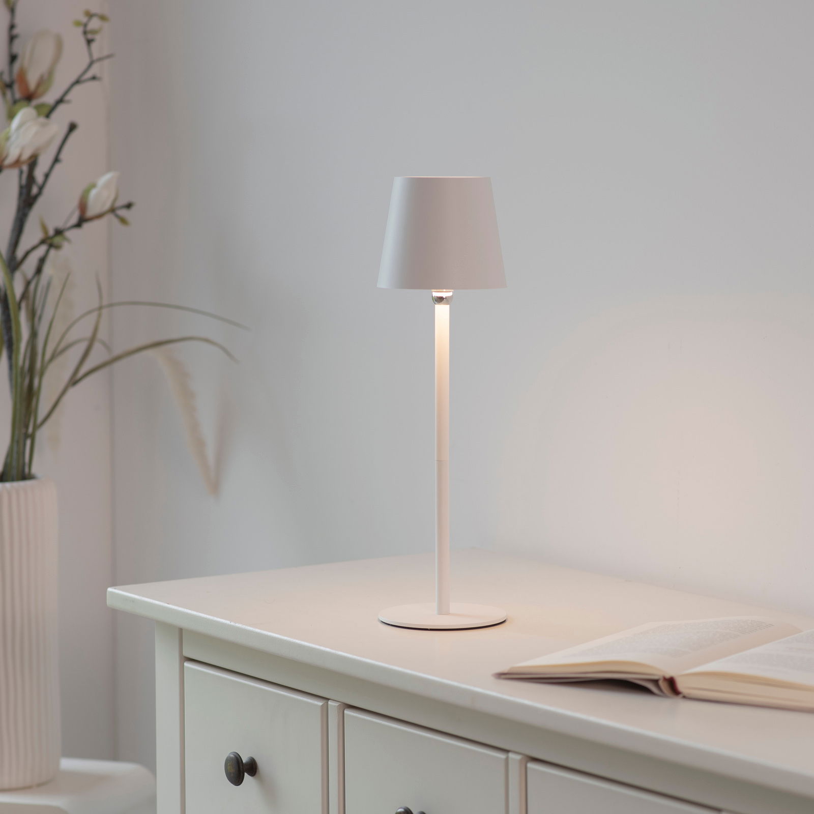 Elegante Akku-Tischleuchte BOTERIA in Weiß auf einem Tisch, seitliche Perspektive