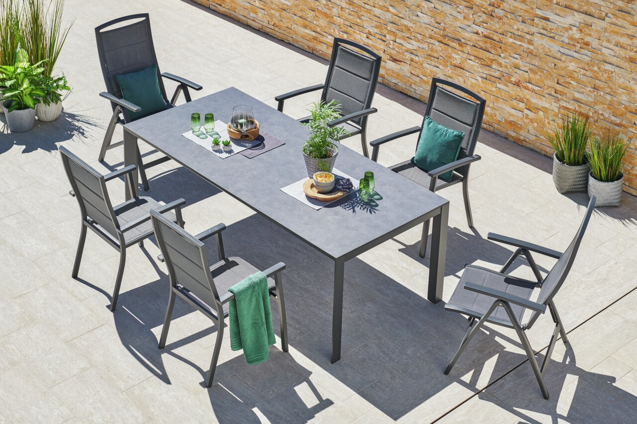 Moderner Stapelsessel auf einer Terrasse, umgeben von einem Tisch und weiteren Stühlen, aus der Vogelperspektive fotografiert.