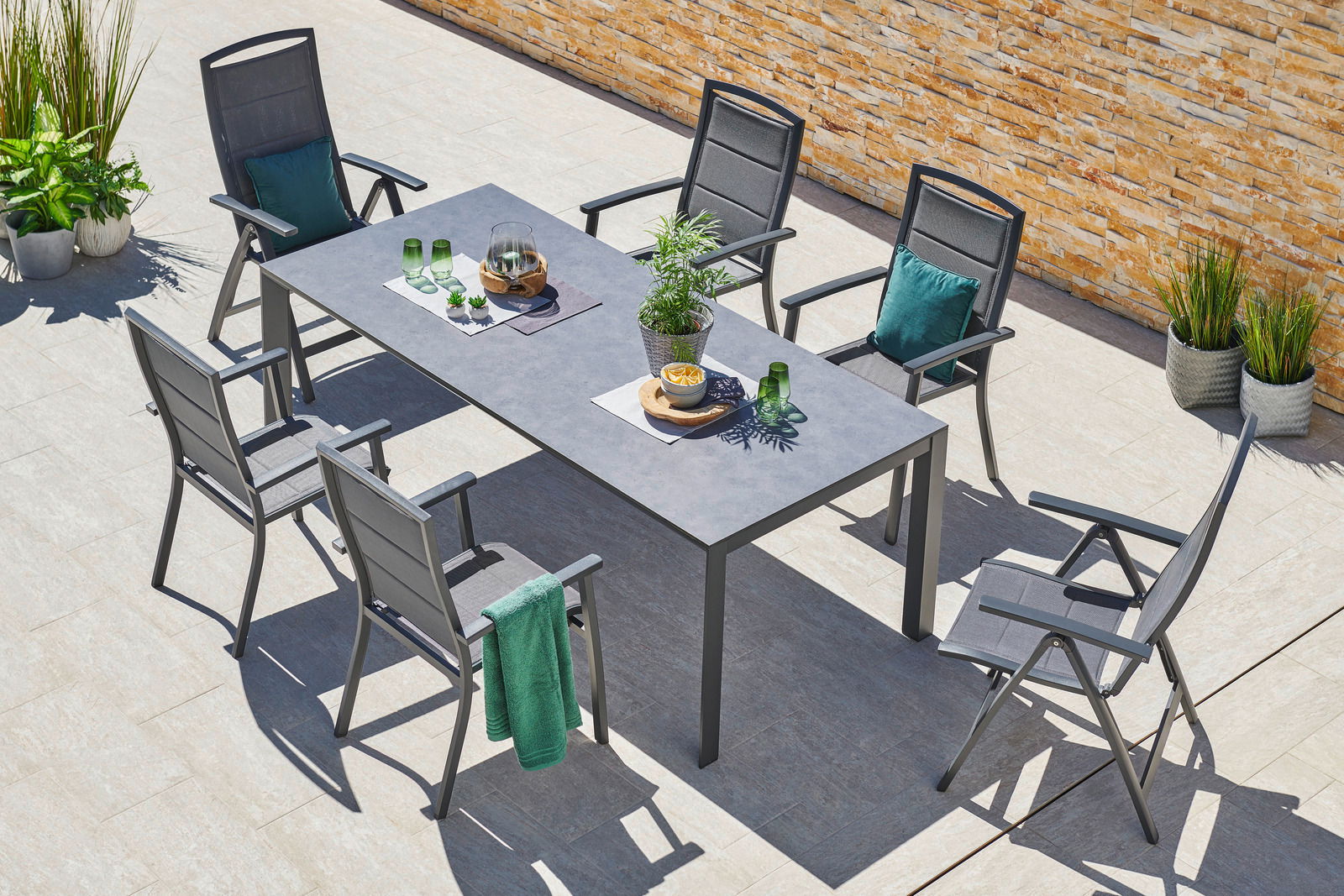 Moderner Stapelsessel auf einer Terrasse, umgeben von einem Tisch und weiteren Stühlen, aus der Vogelperspektive fotografiert.