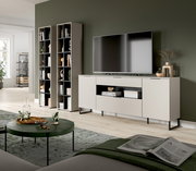 Modernes Wohnzimmer-Setup mit hellem TV-Lowboard auf schwarzen Metallfüßen und großem Flachbildfernseher, daneben zwei hohe offene Regale; Ansicht schräg von vorne aus dem Wohnbereich.