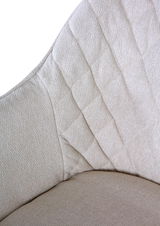 Nahaufnahme eines beigen Armlehnstuhls mit gestepptem Stoffmuster, seitliche Perspektive