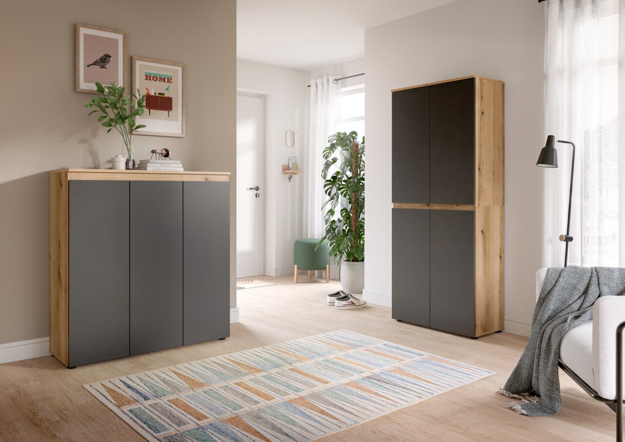 Modernes Wohnambiente mit zwei Schränken in Holzoptik und anthrazitfarbenen Fronten, links ein niedriges Sideboard und rechts ein hoher Schrank, beide in frontaler Perspektive leicht schräg von vorn fotografiert.