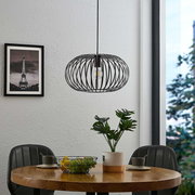 Moderne Hängeleuchte mit schwarzem, drahtigem Design über einem Esstisch, seitliche Perspektive.