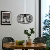 Moderne Hängeleuchte mit schwarzem, drahtigem Design über einem Esstisch, seitliche Perspektive.