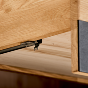 Nahaufnahme eines TV-Lowboards aus Holz mit Metallbeschlägen, Perspektive von unten.
