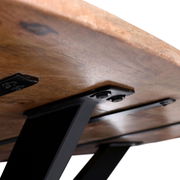 Nahaufnahme der Unterseite eines Esstisches mit massiver Holzplatte und stabilen schwarzen Metallbeinen, Perspektive von unten.