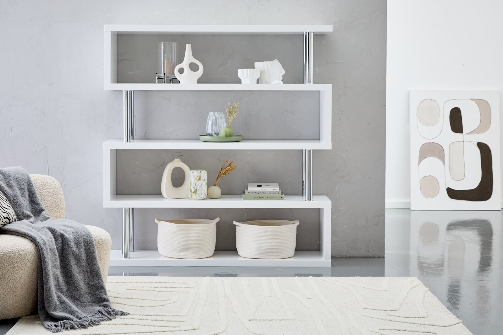XORA Plank KAZUMI Modernes, großes XORA Regal KAZUMI in Weiß mit vier Regalböden, dekoriert mit Vasen und Körben, seitliche Perspektive.