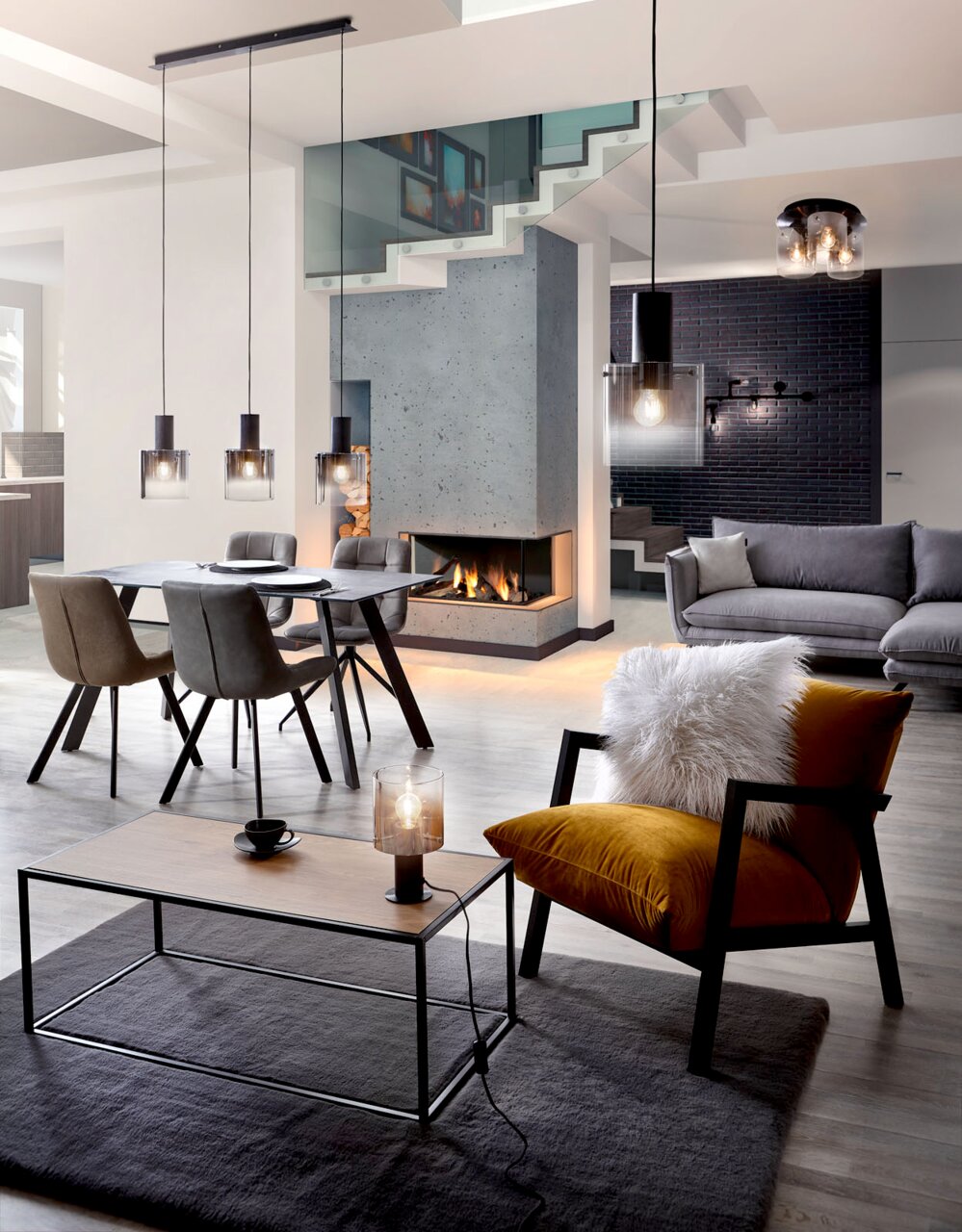 Een moderne woonkamer met stijlvolle hanglampen boven een eettafel, een comfortabele fauteuil met kussens en een salontafel. Aanzicht van voren.