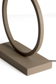 Nahaufnahme eines modernen, minimalistischen Lampenfußes in Ringform aus mattem Material, seitliche Perspektive.