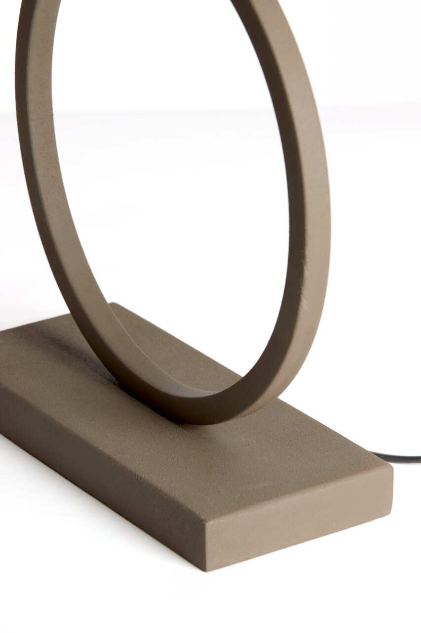 Close-up van een moderne, minimalistische lampvoet in de vorm van een ring, gemaakt van mat materiaal, gezien vanaf de zijkant.