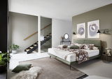 Modernes Boxspringbett in einem stilvoll eingerichteten Schlafzimmer mit grüner Wand und dekorativen Kissen, seitliche Perspektive.