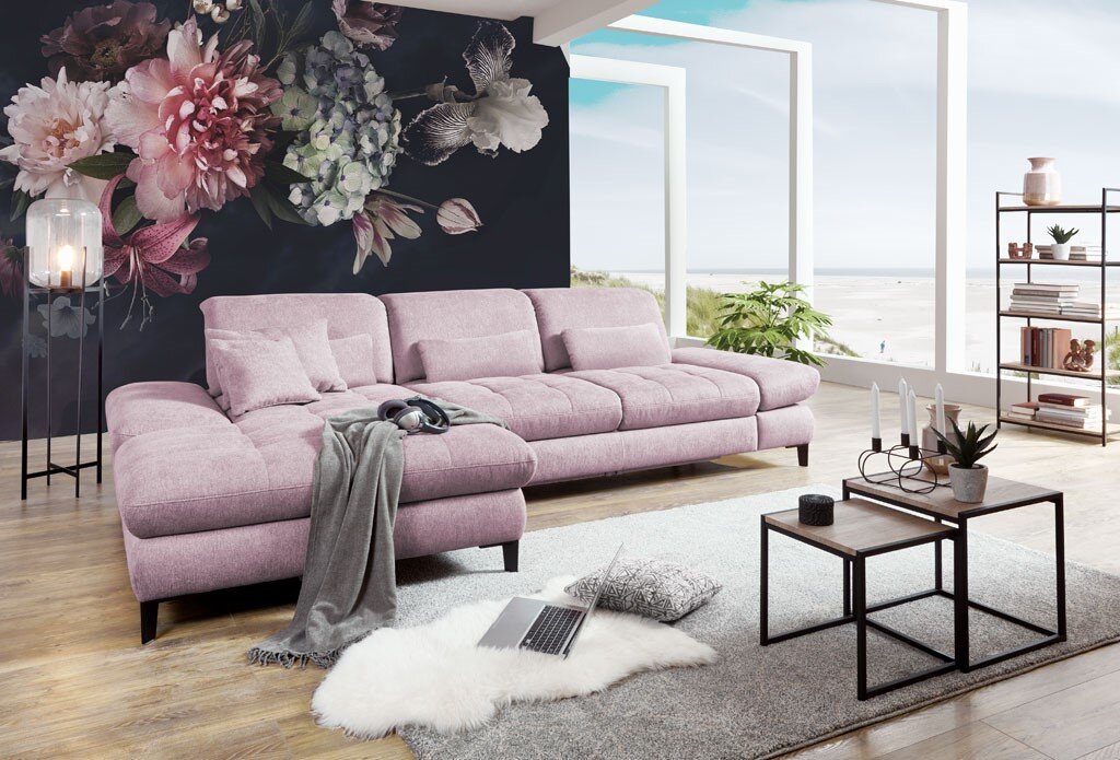 Grote, moderne, roze hoekbank in een stijlvol ingerichte woonkamer met uitzicht op zee. Aanzicht van linksvoor.