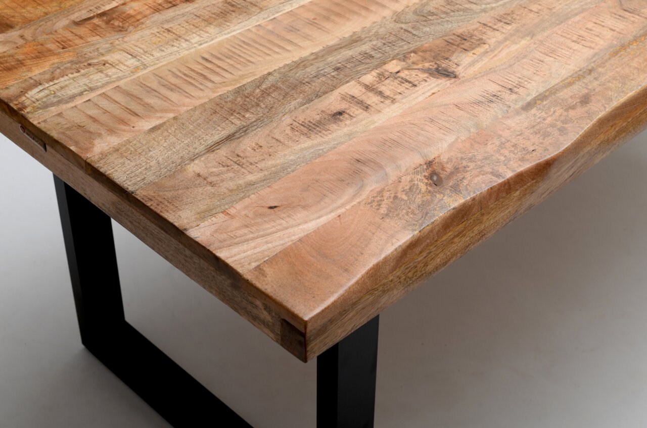 Nahaufnahme eines Esstisches aus Holz mit natürlicher Maserung und schwarzen Metallbeinen, Perspektive von oben.