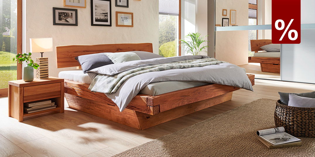 Modern eingerichtetes Schlafzimmer mit massivem Holzbett, hellen Farben und natürlichen Materialien.