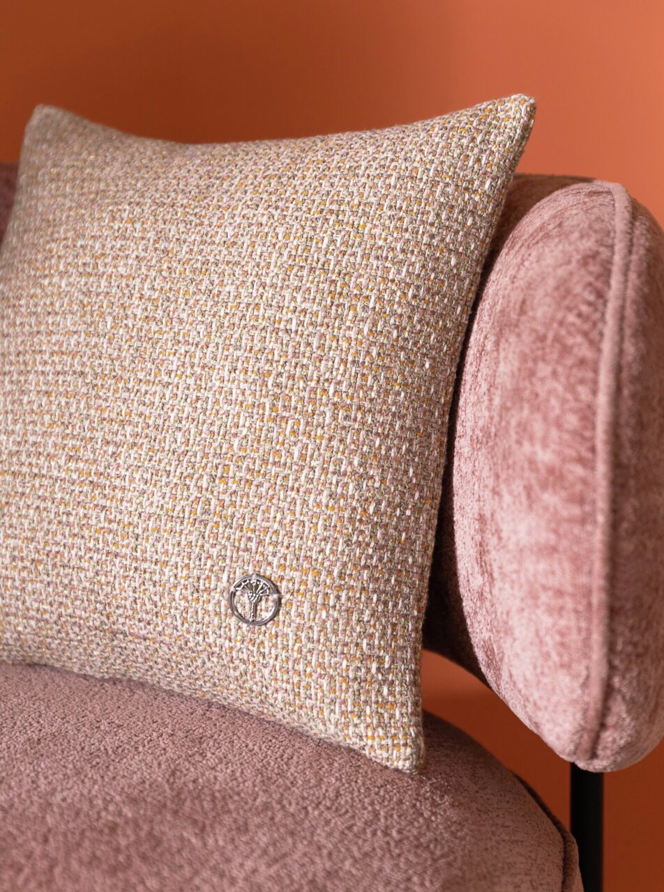 Sierkussenhoes met een beige-gouden weefpatroon op een roze fauteuil, zijaanzicht