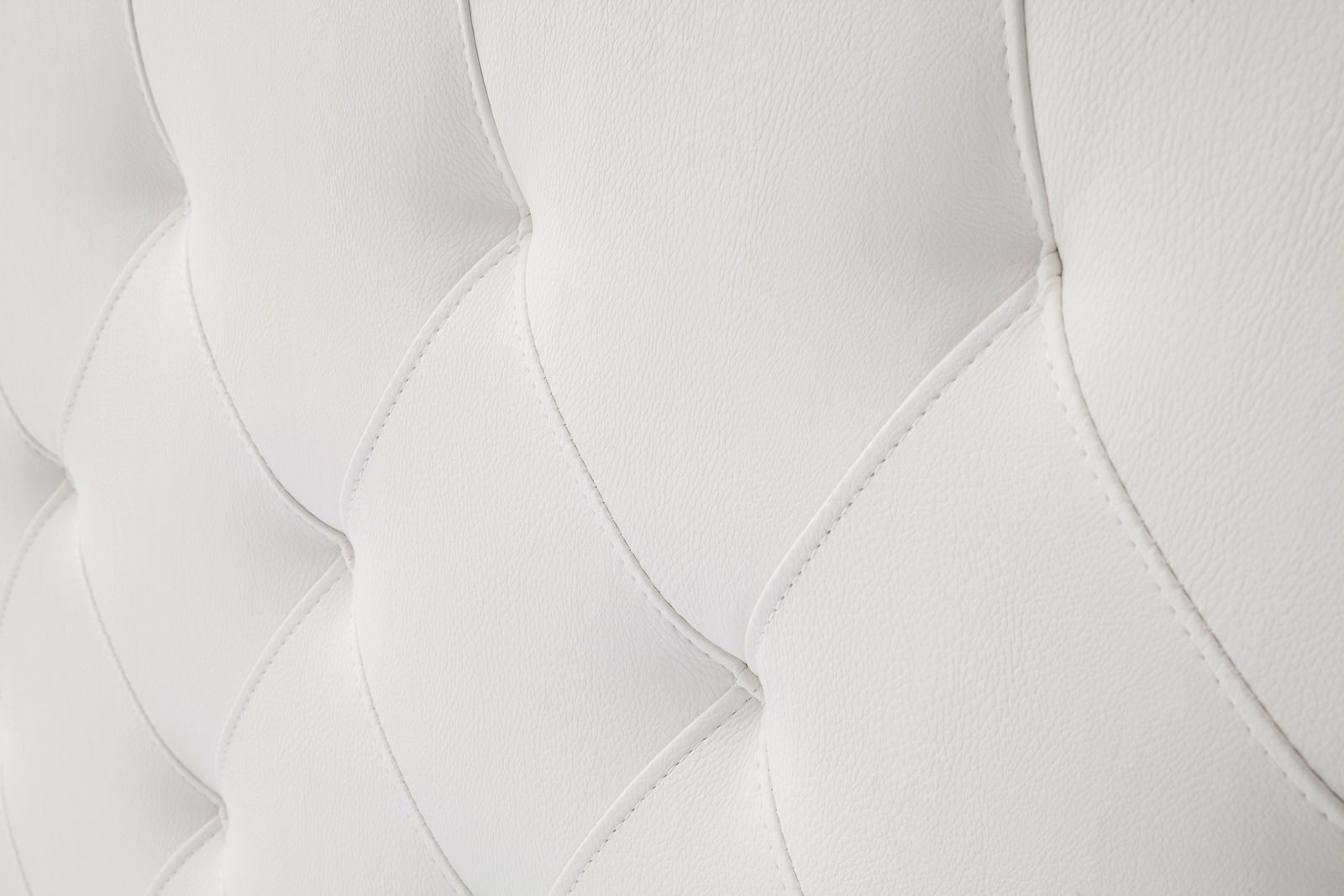 Nahaufnahme eines weißen, gesteppten Polsterbetts mit eleganter Textur.