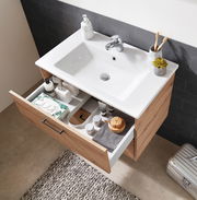 Moderner Waschtischunterschrank aus Holz mit geöffneter Schublade, gefüllt mit Pflegeprodukten, von oben betrachtet.