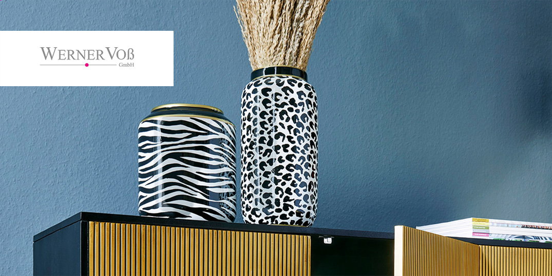 Twee decoratieve vazen met dierenmotief staan op een moderne kast voor een blauwe muur.