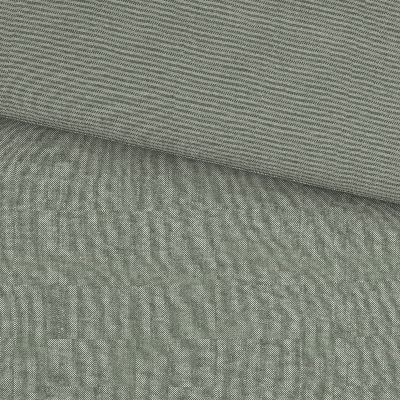 Grüne Wendebettwäsche mit feinem Streifenmuster und einfarbiger Seite, aus der Vogelperspektive fotografiert.