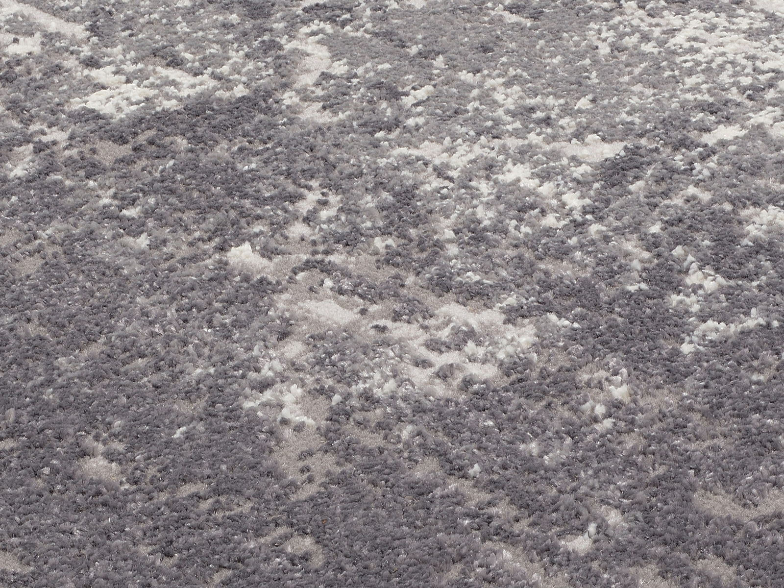 Nahaufnahme eines Designer-Teppichs mit grauem und weißem Muster, aus der Vogelperspektive aufgenommen.