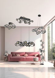 Moderne Wohnzimmeransicht mit mehreren Leuchten der Serie Nancy, darunter eine Stehleuchte, Pendelleuchten und eine Tischleuchte, in einem eleganten, geschwungenen Design mit Glasdetails.