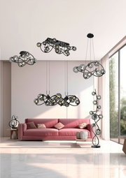 Moderne Wohnzimmeransicht mit mehreren Leuchten der Serie Nancy, darunter eine Stehleuchte, Pendelleuchten und eine Tischleuchte, in einem eleganten, geschwungenen Design mit Glasdetails.