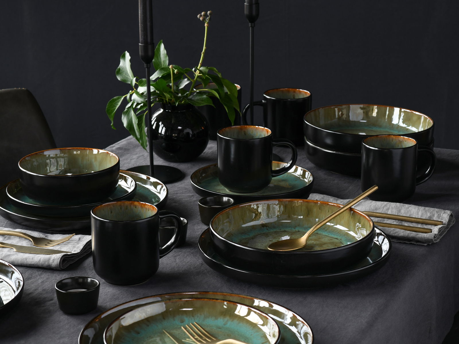 Creatable Kombiservice 30-tlg. NORDIC FJORD Elegantes Kombiservice 30-tlg. Green in Schwarz und Grün, auf einem gedeckten Tisch mit goldfarbenem Besteck und Pflanzen im Hintergrund, aus der Vogelperspektive fotografiert.