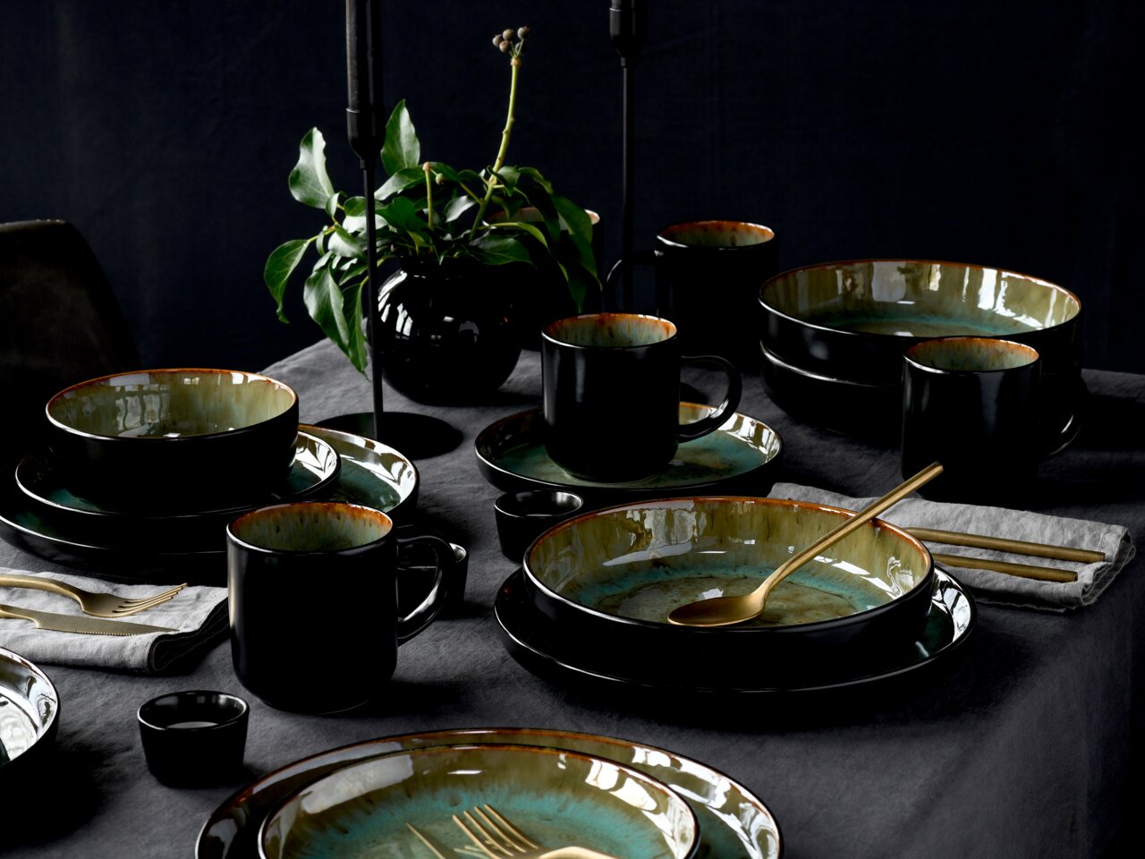 Creatable Kombiservice 30-tlg. NORDIC FJORD Elegantes Kombiservice 30-tlg. Green in Schwarz und Grün, auf einem gedeckten Tisch mit goldfarbenem Besteck und Pflanzen im Hintergrund, aus der Vogelperspektive fotografiert.
