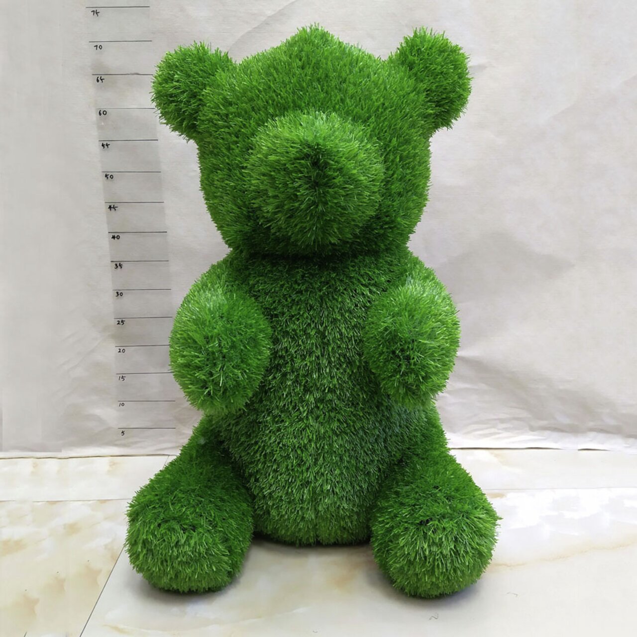 Grüne Bärenfigur aus Gras, frontalansicht, Gartendekoration