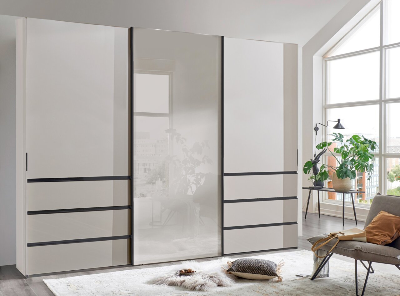 Moderner Schwebetürenschrank in einem hellen Raum mit großen Fenstern, seitliche Perspektive